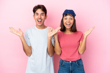 Young couple isolated on pink background with surprise and shocked facial expression