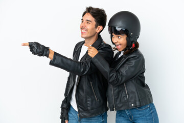 Young mixed race couple with a motorcycle helmet isolated on white background pointing to the side to present a product