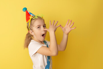 Funny kid clown against yellow background. Happy child playing with festive decor. Birthday and 1 April Fool's day concept