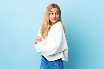 Young Uruguayan blonde woman over isolated blue background making doubts gesture while lifting the shoulders