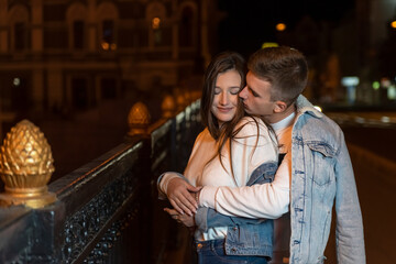Young guy and girl hugging on the background of the night city. Outdoors relationship