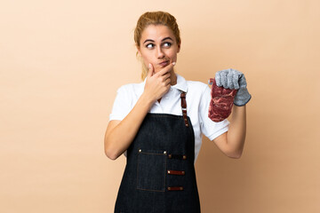 Butcher woman wearing an apron and serving fresh cut meat over isolated background thinking an idea