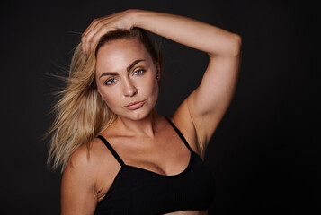Fototapeta premium Confident beautiful fitness young woman with a healthy toned body, clean glowing tanned skin against colored background