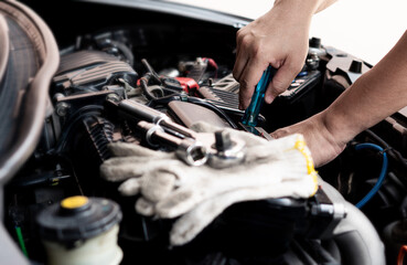 Car service man use screwdriver to remove part of the car in the engine room and wrench and glove on engine car service concept
