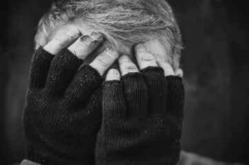 Traurige Aufnahme eines armen Menschen mit Handschuhen und dreckigen Händen