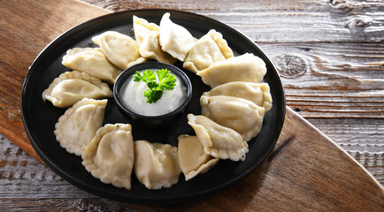 Composition with a plate of classic pierogies with sour cream