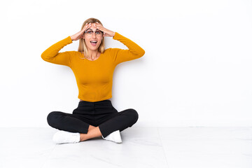 Obraz premium Blonde Uruguayan girl sitting on the floor with surprise expression