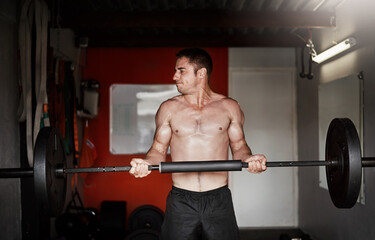 Increasing his strength. Cropped shot of a handsome and muscular young man working out with a barbell in the gym.