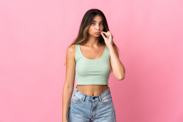 Young caucasian woman isolated on pink background showing a sign of silence gesture