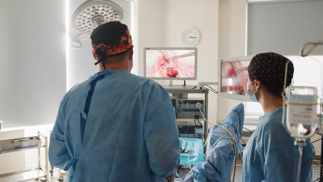 Operation using laparoscopic equipment. Process of gynecological surgery operation using equipment. Group of surgeons in operating room with surgery equipment. Shooting from the back of surgeons work