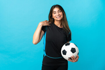 Young football player woman isolated on blue background laughing