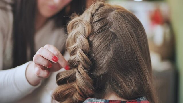 The girl makeup artist makes a braid for the model.