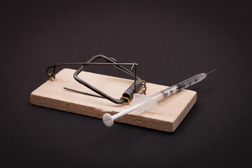 Drug Addict, Heroin Hazard or Dose Trap Concept - Disposable Insulin Syringe with Drug Dose Inside Lying in Wooden Mousetrap on Black Background