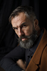 Obraz premium Portrait of mature bearded man in coat. Dark background. High quality photo