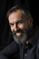 Emotional portrait of mature bearded man. Dark background. High quality photo
