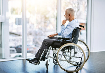 I miss the days of being mobile. Shot of a mature man sitting in a wheelchair and looking out the...