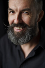 Emotional portrait of mature bearded man. Dark background. High quality photo