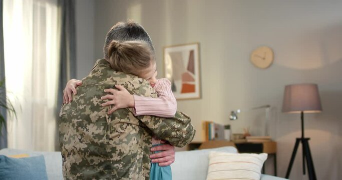 Positive daughter welcoming military father with hugs