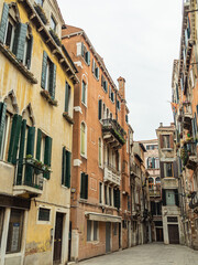 A quiet, empty Venetian street with beautiful pastel colored buildings taken during the winter on an overcast day - Venice, Italy.
