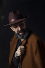 Portrait of mature bearded man in coat and hat. Mystical thriller concept. High quality photo