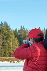 trap shooting, man in the red baseball cap and red  jacket shoots a double-barreled shotgun