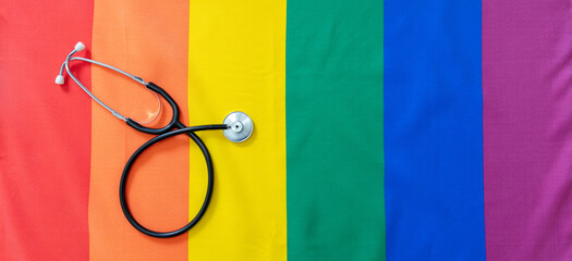 LGBT Health care. Medical Stethoscope on rainbow pride flag background, overhead view