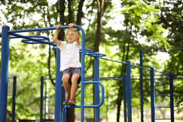sports boy climbed on the horizontal bars and hangs on them