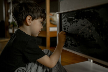 Fototapeta na wymiar a little boy draws with chalk on a graphite board