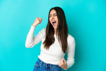 Fototapeta premium Young caucasian woman isolated on blue background celebrating a victory