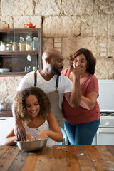 African American family having fun in their home kitchen while cooking a cake together
