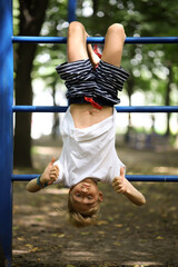 the boy on the sports ground caught his feet on the stairs and hangs upside down