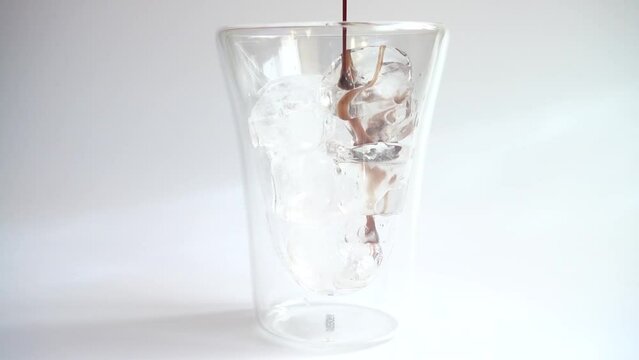 Add chocolate topping to an ice glass. Slow motion.