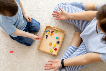 Montessori material. Woman and a boy are studying a puzzle with keys and locks.