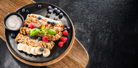 A plate of pancakes with cheese and fruits