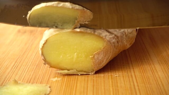 The cook cuts ginger root with a knife. Slow motion.