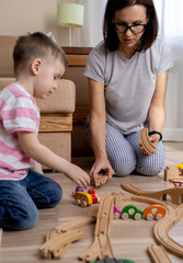 Montessori material. Mom and son learn transport through the game. Wooden railroad.