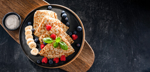 A plate of pancakes with cheese and fruits