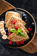 A plate of pancakes with cheese and fruits