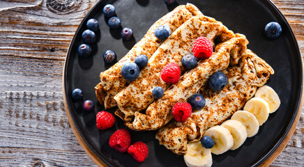 A plate of pancakes with cheese and fruits