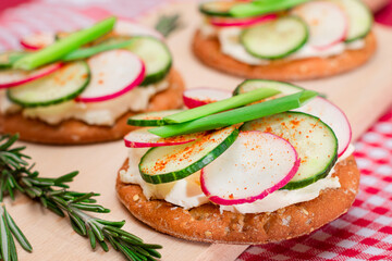 Light Breakfast or Diet Eating - Crispy Cracker Sandwich with Cream Cheese, Fresh Cucumber, Green Onions and Radish on Wooden Cooking Board on Magenta Background