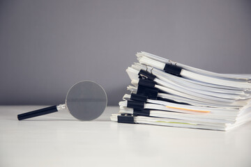 Magnifying glass with stack of documents