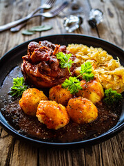 Roast pork knuckle with potatoes and fried cabbage   on wooden table
