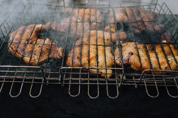 Chicken thighs are fried on the grill in a barbecue. Picnic in nature.