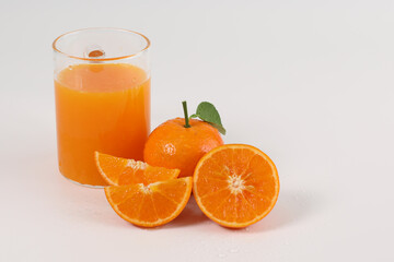 oranges, halved oranges, healthy fruit, mandarin oranges, orange juice in glass, vitamin C, against a white background with refreshing drops of water