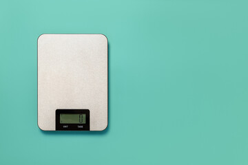 Digital kitchen scales against turquoise background. Electronic scales for food weight measurement....