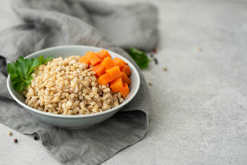 Fototapeta na wymiar boiled pearl barley with butter and carrots in a gray plate