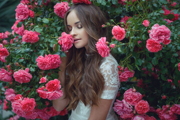 Naklejka premium Beautiful portrait of a woman in poses. A brunette woman is standing next to roses in nature.