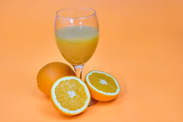 Whole and sliced oranges with a glass of squeezed juice