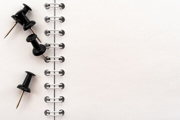 Black pins for notes or office paper on a notebook. Place for an inscription. Stationery