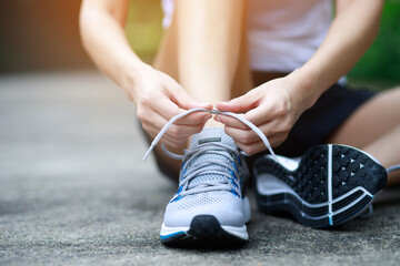 Running shoes. close up female athlete tying laces for jogging on road. Runner ties getting ready for training. Sport lifestyle. copy space banner.